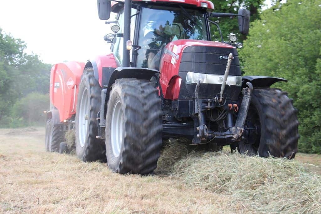 L'ensemble tracteur - presse - enrubanneuse de la cuma avale un andain et pond des boules prêt-à-ramasser.